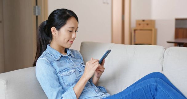 Woman use of mobile phone on sofa - Foto, imagen
