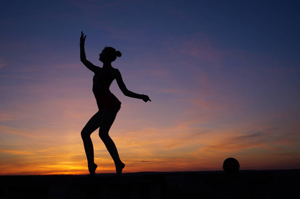 danseuse dans la danse fait les fentes dans l'air contre le coucher du soleil / - Photo, image