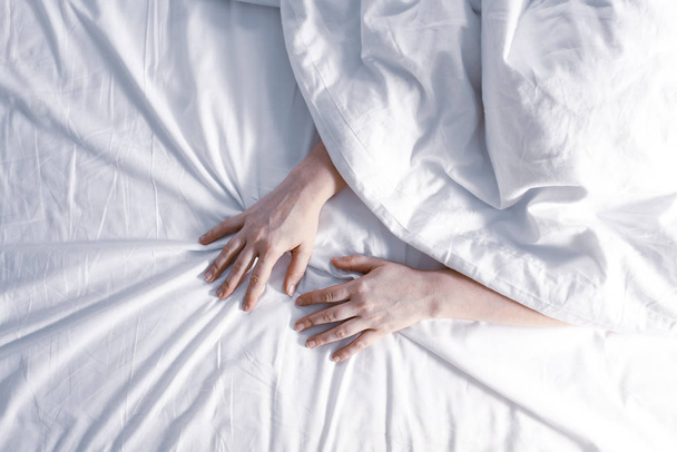 Insomnia concept. Womans hands on white sheet. - Foto, imagen