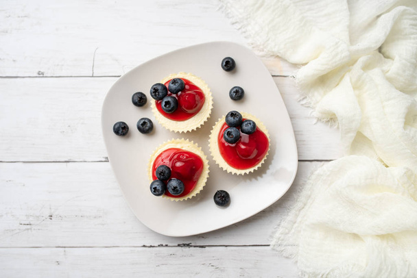 Mini cheesecakes with cherry and blueberry topping, sweet summer treat - Foto, Bild
