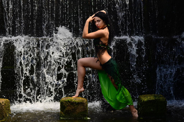 Joven modelo morena posando contra una cascada
 - Foto, Imagen