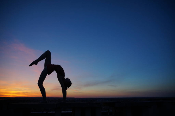 χορευτής στο χορό κάνει τις σχισμές στον αέρα κατά το ηλιοβασίλεμα / - Φωτογραφία, εικόνα