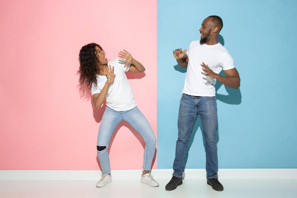 Young emotional man and woman on pink and blue background - Foto, afbeelding