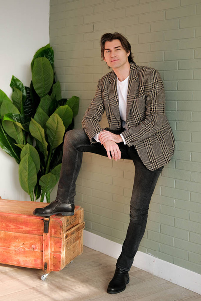 Tall handsome man standing next to grey wall and wooden box - Φωτογραφία, εικόνα