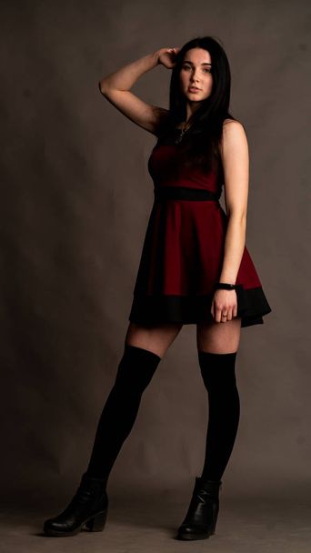 young brunette woman in stylish clothes posing in dark studio   - Photo, image