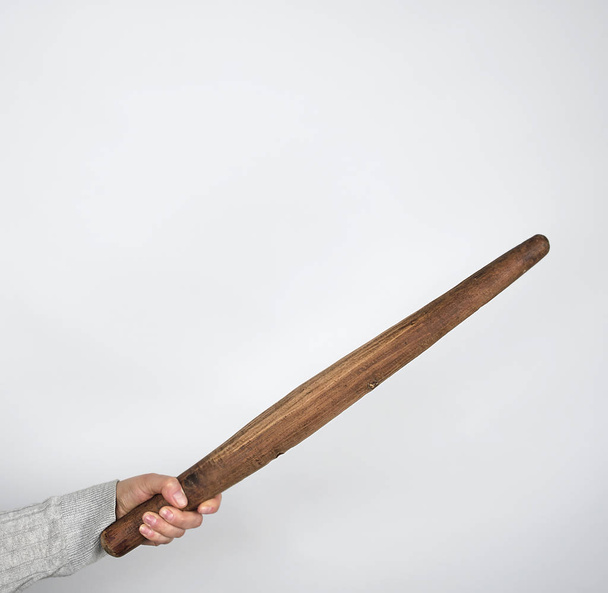 hand holding a very old wooden rolling pin on a gray background - Fotó, kép