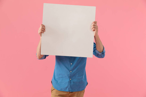 casual guy covering face with empty board - Foto, immagini