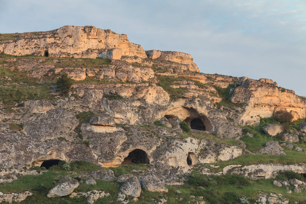 Холм перед Матерой с вырезанными в скале пещерами. Матера, Италия
 - Фото, изображение