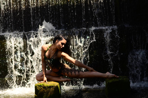 Jovem morena modelo posando contra uma cachoeira
 - Foto, Imagem