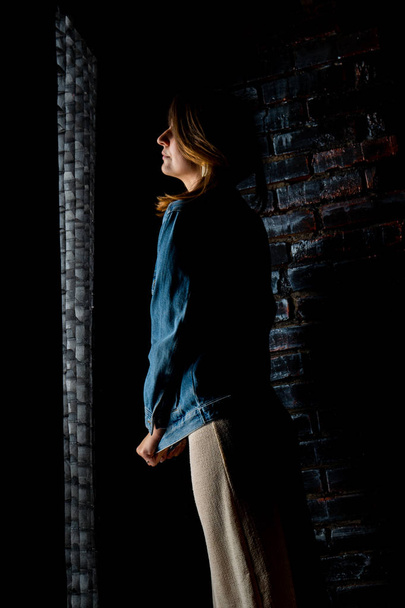 brunetka dziewczyna w zielona kurtka i biustonosz stoi w pobliżu biały mur. - Zdjęcie, obraz