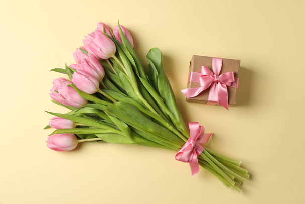Ramo de tulipanes rosados y presentes sobre fondo beige, vista superior
 - Foto, imagen
