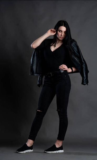 young brunette woman in stylish clothes posing in dark studio   - Φωτογραφία, εικόνα
