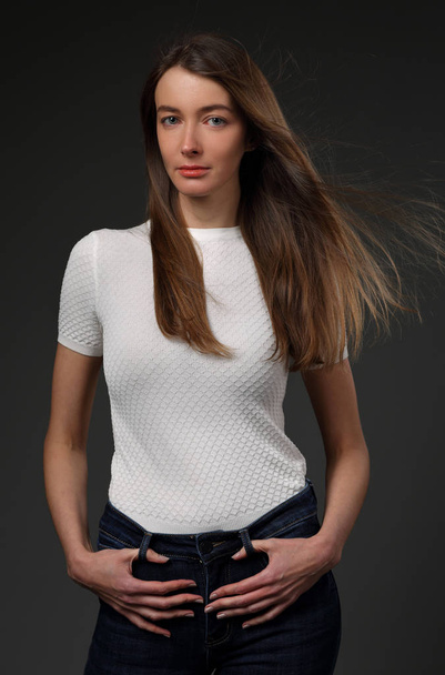 Beautiful girl in a white t-shirt and jeans on a gray background - Fotografie, Obrázek