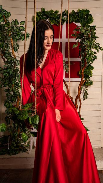 beautiful young woman in a long red dress on a swing - Foto, immagini