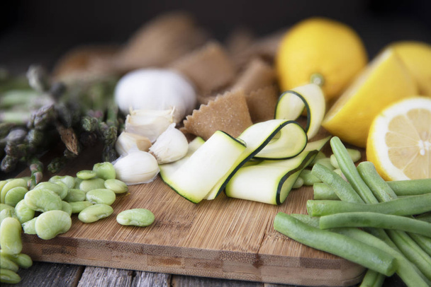 Fresh ingredients for pasta, zucchini, lima beans, green beans, lemon, garlic and homemade whole wheat pappardelle pasta. - Photo, Image