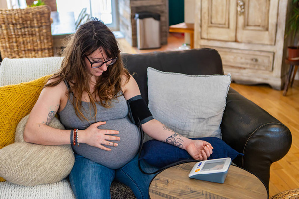 Mujer embarazada utiliza medidor de presión arterial
 - Foto, imagen