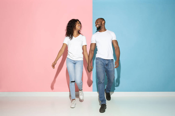 Young emotional man and woman on pink and blue background - Fotó, kép