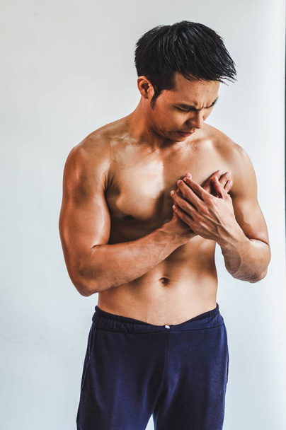 Asian man with muscular Injury to the chest from exercise on Whi - Photo, image