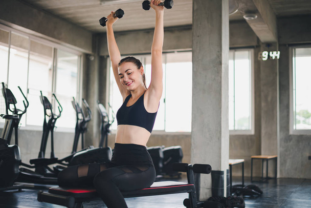 Beautiful girl caucasian is exercising with lifting dumbbell in  - 写真・画像