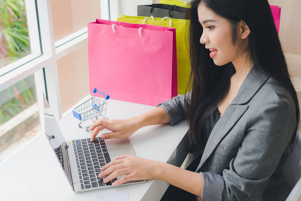 Aziatisch meisje zit online winkelen. Via telefoon en creditcard. - Ja. - Foto, afbeelding