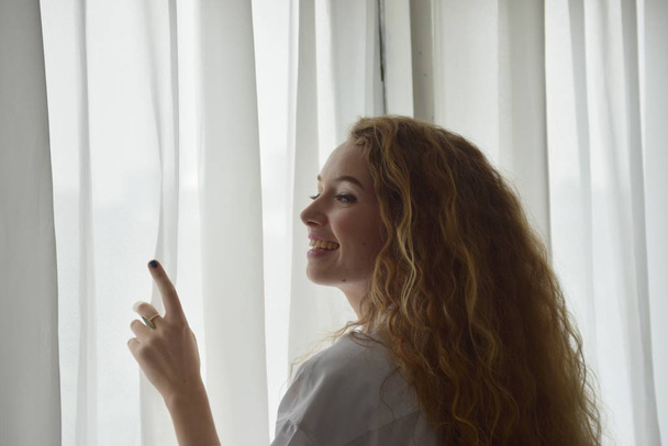 Krásná mladá žena v blízkosti okna doma - Fotografie, Obrázek