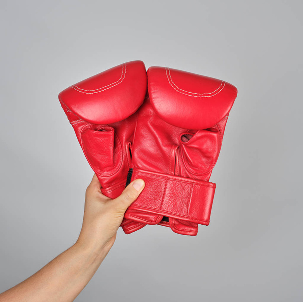 pair of red leather boxing gloves in female hand, gray background - Photo, image