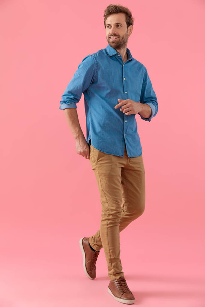 giovane uomo casual in camicia di jeans che cammina e sorride
 - Foto, immagini