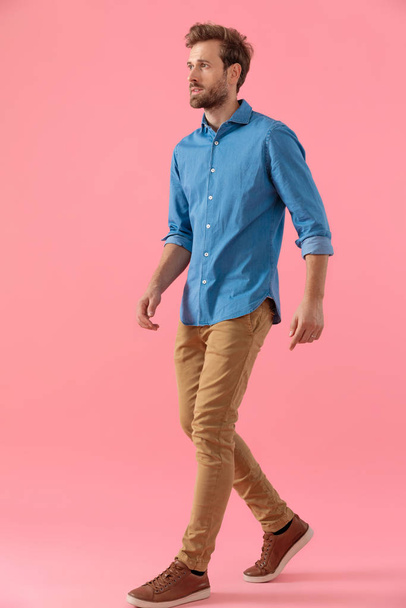 joven hombre casual en camisa de mezclilla mirando a un lado y caminando
 - Foto, Imagen