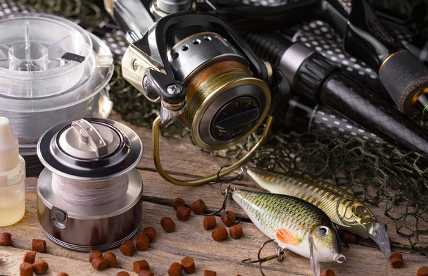 Fishing rods and spinnings in the composition with accessories for fishing on the old background on the table - Photo, Image