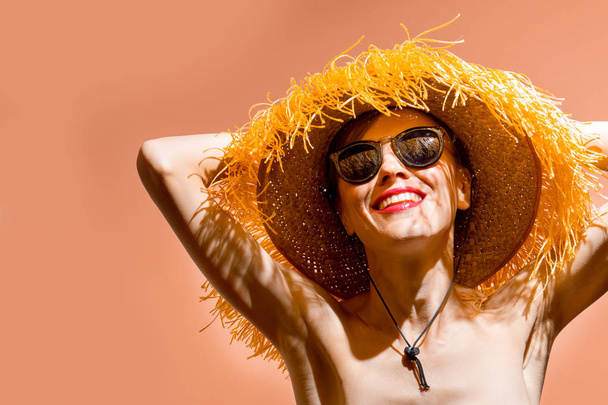 Muotokuva hymyilevä houkutteleva nainen bikinit ja hattu poseeraa vaaleanpunainen tausta
 - Valokuva, kuva