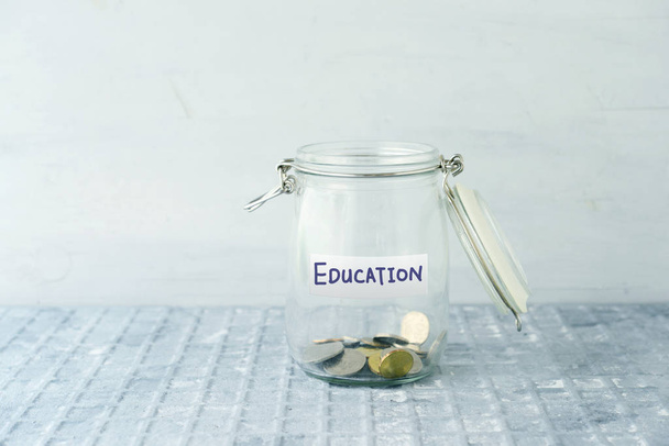 Coins in glass money jar with education label, financial concept. - 写真・画像