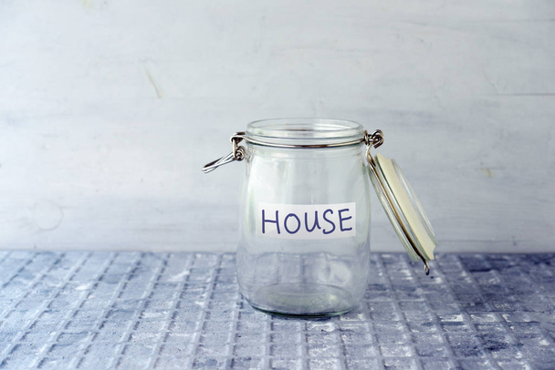 Empty glass money jar with house label, financial concept. - Foto, Imagem
