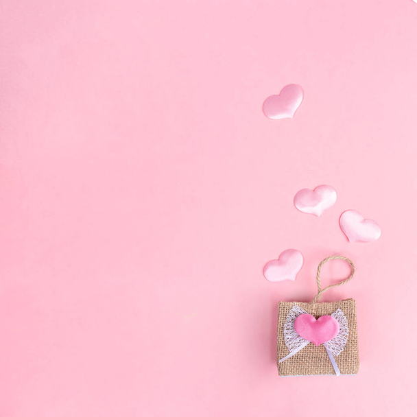 Decorative wicker handbag and four flying out of it pink hearts on pink background. Valentines day shopping concept.  - 写真・画像