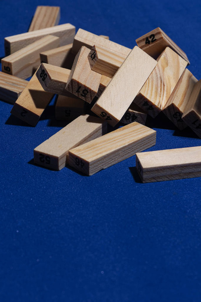 Pila de Bloques de madera sobre tabla en color azul clásico con luz dura y sombras marcadas y los cubos de madera estn numerados. - Foto, Imagen