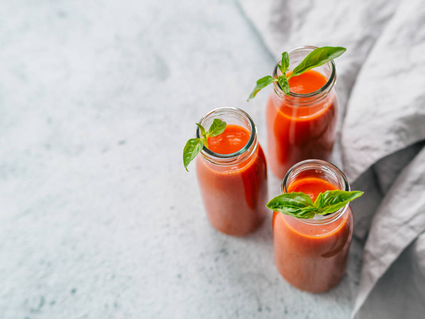 Delicious gaspacho soup in glass bottles. Traditional spanish cold soup puree gaspacho or gazpacho on gray cement background with copy space for text. View from above or top view or flat lay - Photo, image
