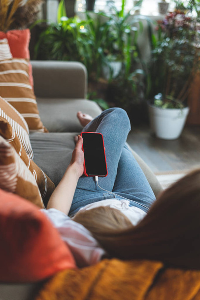 Young adult woman resting at home with smartphone in hands - Foto, Bild