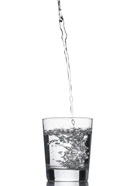 Water poured into glass. Isolated on white background. - 写真・画像