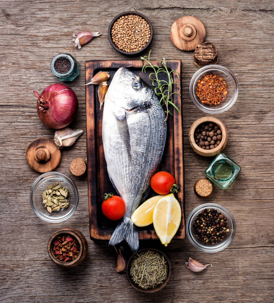 Fresh fish with ingredients for cooking.Fresh dorado fish on wooden cutting board - Foto, Bild