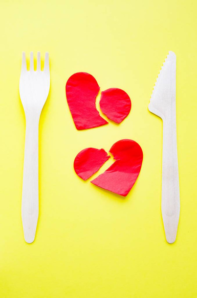 Bamboo biodegradable fork made of natural eco recycle reusable material and two broken paper hearts on yellow. - Valokuva, kuva