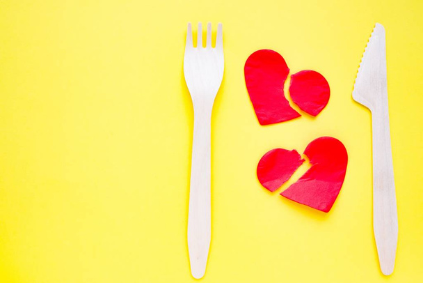 Bamboo biodegradable fork made of natural eco recycle reusable material and two broken paper hearts on yellow. - Valokuva, kuva