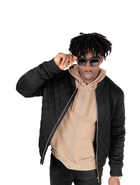 A close up portrait picture of an African American man is casual .clothing putting on his sunglasses, isolated for white background. - Foto, imagen