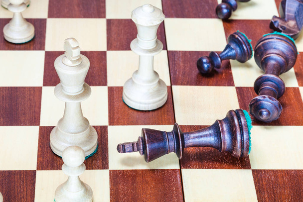 business concept - falling black chess pieces and wining white chessmen - 写真・画像