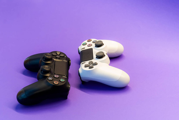 weiße und schwarze Controller auf violettem Hintergrund Rückseite - Foto, Bild