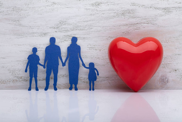 Close-up Of A Family Holding Hands Besides Red Heart Shape In Front Of Wooden Wall - Photo, Image