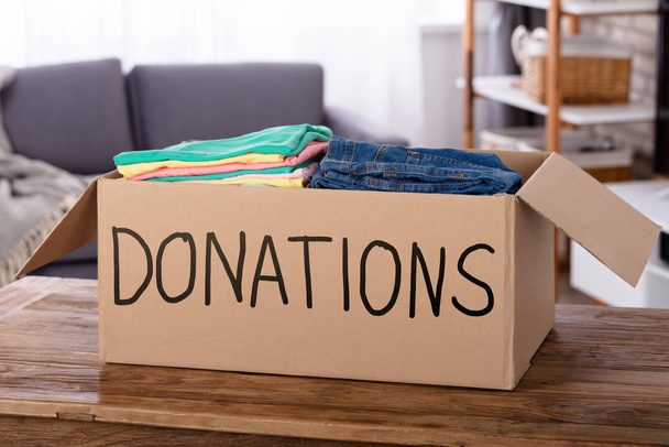 Close-up Of Clothes In Donation Box On Wooden Desk - Foto, immagini