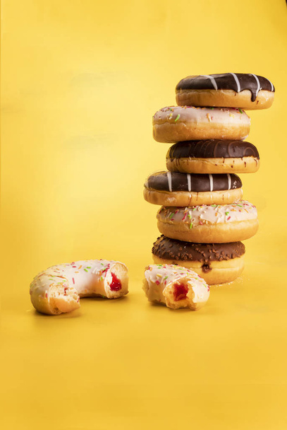 Vertical poster with pile of various donuts on yellow background. Sweet pastries of Fat Thursday. Doughnuts  - Фото, зображення