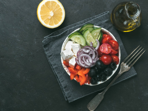 Greek Salad Bowl on dark black background, copy space. Above view of Bowl Greek Salad. Trendy food. Idea, recept and concept of modern healthy food. Toned image. - 写真・画像