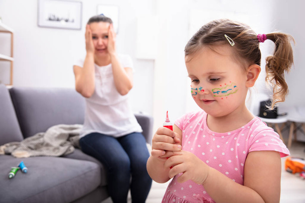 Shocked Mother Sitting On Sofa Looking At Her Daughter Painting Face With Color Tube - Fotoğraf, Görsel