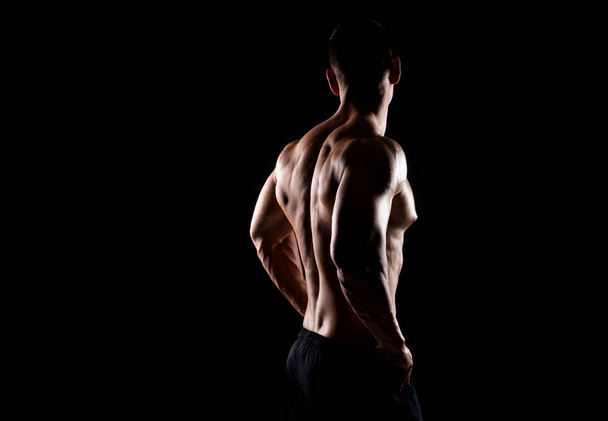 Sterke, fitte en sportieve bodybuilder man over zwarte achtergrond. Sport en fitness concept. - Foto, afbeelding