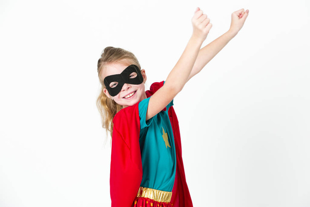 beautiful blond supergirl with black mask and red cape posing in front of white background - Fotoğraf, Görsel